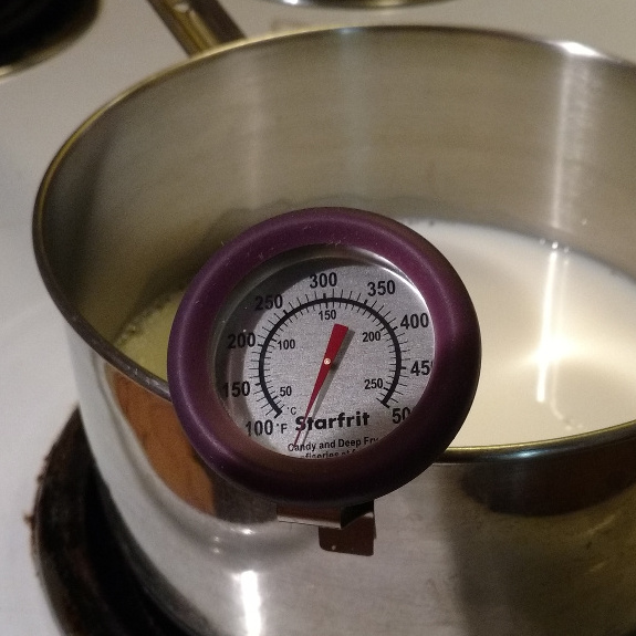 Milk heating on stove with thermometer